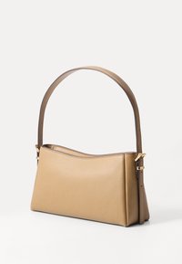 Sac à main en cuir fauve avec une texture lisse, une forme structurée et une anse incurvée unique. Présente des accents métalliques dorés et un design minimaliste.