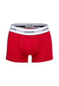 Boxer in cotone rosso con una vita elastica bianca che presenta il logo Lacoste. Il design include una tasca sagomata per il supporto.