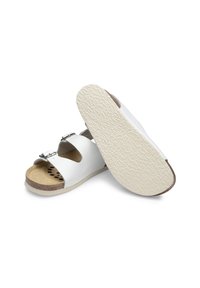 White leather sandals with two adjustable silver buckles, contoured cork footbed, and textured rubber sole for grip.