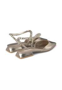 Ballerines slingback dorées en métal avec un bout pointu et un talon plat, ornées d'un accent en strass transparent le long de la bride pour un détail supplémentaire.