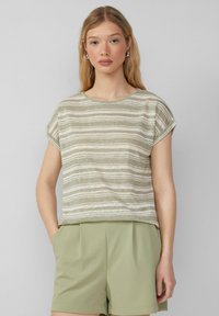 Jasnozielona, w paski, krótka koszulka z rękawem, wykonana z miękkiego, teksturowanego materiału. Posiada okrągły dekolt i podwinięte mankiety. W połączeniu z jasnozielonymi szortami.