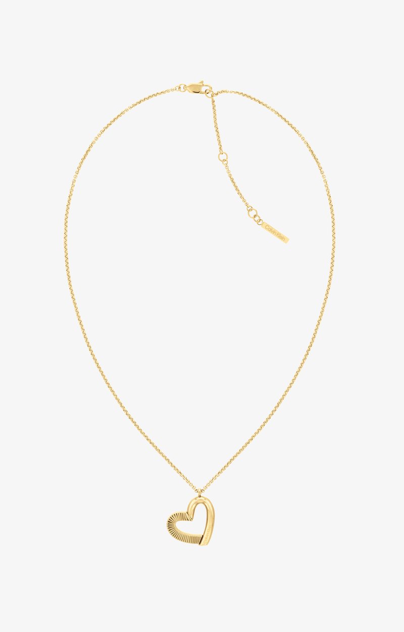Kultaketju, jossa on sydämen muotoinen riipus, jossa on teksturoidut yksityiskohdat. Ketju koostuu hienoista lenkeistä ja pienestä bränditunnuksesta lähellä sulkijaa.