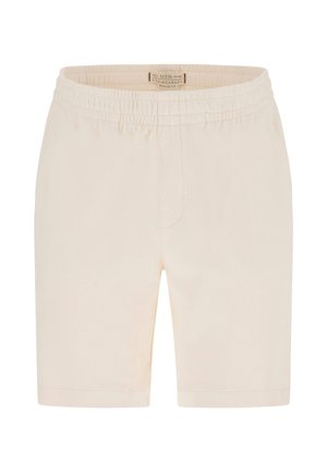 Beżowe szorty z elastycznym pasem, o prostym kroju, bez widocznych kieszeni, z małą materiałową metką marki wszytą wewnątrz pasa.
