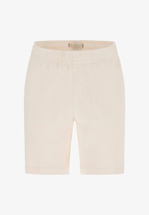 Shorts beige à taille élastique avec une coupe droite et sans poches visibles, présentant une petite étiquette de marque en tissu à l'intérieur de la ceinture.