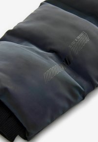 Schwarze Pufferjacke mit glänzender Oberfläche, horizontaler Steppung, gerippten Bündchen und gedruckten Zahlen auf der Vorderseite.