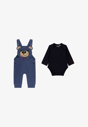 Salopette in denim con design di faccia d'orso e testo rosso, abbinata a un body a maniche lunghe nero con chiusure a scatto sul fondo.