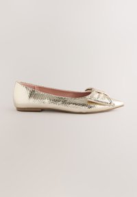 Aukso spalvos butas batelis su gyvatės odos raštu, smailiu noseliu ir kaspino detalė priekyje. Lygi tekstūra su žemu, plokščiu padu.