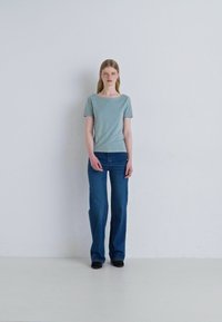 Un tricou scurt cu mâneci scurte, de culoare albastru deschis, asociat cu blugi dark blue evazați. Întreaga ținută are un design simplu și o croială lejeră.