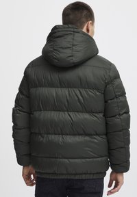 Mørkegrøn pufferjakke med et vandret syet design, der har en hætte og en glat, blank overflade.