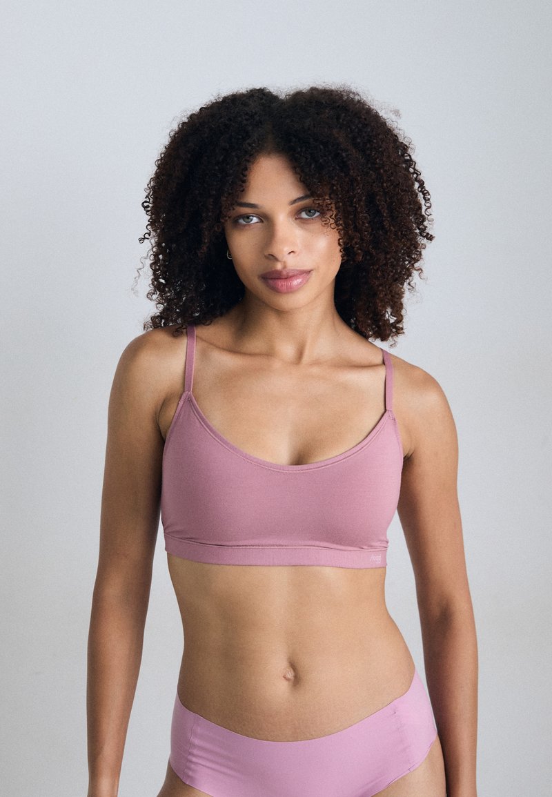 Soutien-gorge seamless rose clair avec de fines bretelles, en tissu doux et à la texture lisse, associé à un bas de bikini assorti. Détails de conception minimalistes.
