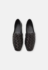 Černé tkané kožené slip-on boty s kulatou špičkou a hladkým vnitřkem. Textura je pletená s plochým designem podrážky.