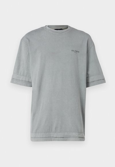 Siva kratka majica s kratkimi rokavi iz mehkega blaga, z okroglim izrezom in napisom "TIšina" natisnjenim v črni barvi na sprednji strani.