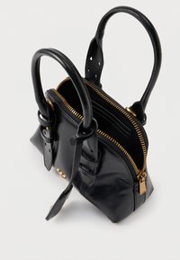 Μαύρη δερματίνη τσάντα χειρός με χρυσό φερμουάρ ανοιχτή, που διαθέτει δύο στρογγυλές λαβές και λεπτομέρειες από λουρί με αγκράφα πάνω σε λευκό φόντο.