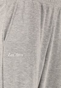 Graue Sweatpants aus weichem Material mit seitlichen Taschen und elastischem Bund. Mit der weißen Stickerei "Les’Arcs" am Bein.