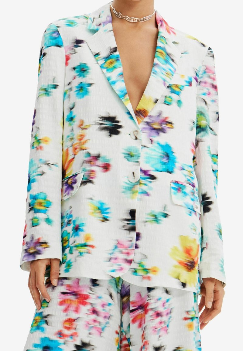 Kwiatowa marynarka w białym kolorze z kolorowymi wzorami w odcieniach niebieskiego, różowego, żółtego i czarnego. Posiada kołnierz z wycięciem i zapięcie na guzik; lekki materiał.