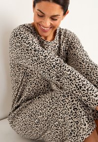 Beige leopardprint kjole med lange ærmer og rund halsudskæring, lavet af blødt stof med en glat tekstur.