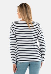 Camicia a maniche lunghe a righe blu navy e bianche con scollatura arrotondata e morbido tessuto in cotone. Presenta una vestibilità rilassata e una leggera apertura laterale all'orlo.