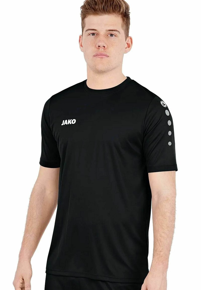 Schwarzes Sport-T-Shirt aus glattem Stoff. Mit dem weißen "JAKO"-Logo auf der Vorderseite und sechs grauen Akzenten auf dem rechten Ärmel.