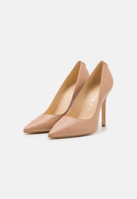 Nude usnjeni čevlji z visokim petam in pointed toe designom, s tankim stiletto peto, ki imajo gladko teksturo in minimalistično blagovno znamko znotraj.