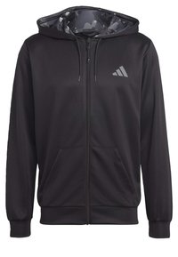 Svart zip-up hoodie med ett inre i kamouflage-mönster, har en framficka och en liten grå logotyp på vänster bröst. Mjuk tyg.