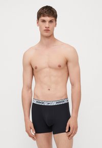 Black boxer briefs made of smooth fabric with a patterned gray waistband featuring the Nike logo. Form-fitting design with a front pouch.
