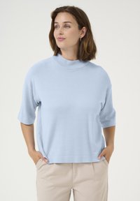 Light blue, short-sleeve top with a mock neck, made from soft fabric. The design is relaxed, featuring a straight cut and rolled cuffs.