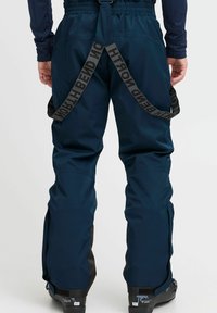 Pantalones de esquí azul marino con tirantes negros ajustables, paneles reforzados y un diseño de pierna recta; cuentan con ventilaciones con cremallera y una textura suave.