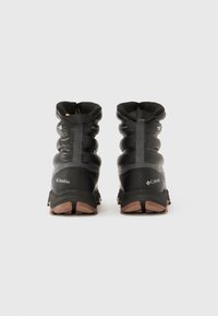 Par av svarta Columbia isolerade vinterstövlar stående upprätt, visade bakifrån på en enkel vit bakgrund.