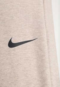 Sudadera beige claro hecha de una tela suave, con el logo de Nike en color negro. Superficie texturizada con un diseño de ajuste casual.