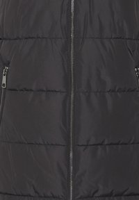 Čierny pufovaný vest, ktorý má zips, horizontálne prešívanú textúru a dve bočné vrecká so zipsami. Hladký, matný povrch.