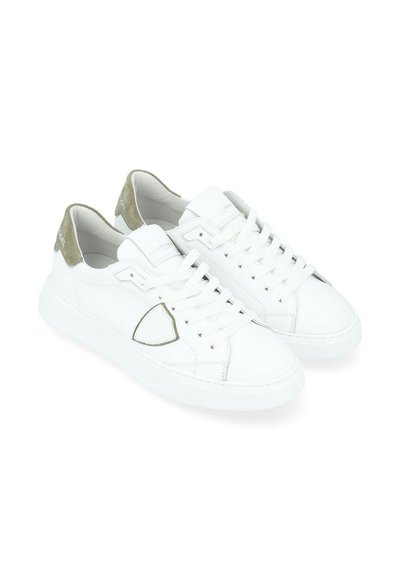 Sneakers bianchi in pelle con una texture liscia, caratterizzati da un accento in suede verde sul tallone, punta arrotondata e lacci bianchi.