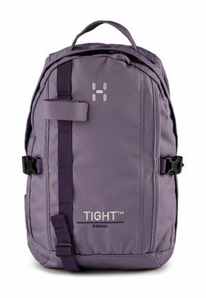Sac à dos compact violet avec poignée supérieure, bretelles réglables, sangle verticale avant et marque "TIGHT™ X SMALL" sur le panneau avant.