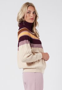 Stickad höghalsetröja med ribbad textur. Dekorerad med horisontella ränder i vinröd, guld, rosa och krämfärgad. Lätt avslappnad passform och längre ärmar.