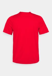 Camiseta roja de manga corta confeccionada con tela suave. Presenta un escote redondo y un corte recto. La vista trasera no muestra logotipos ni gráficos.