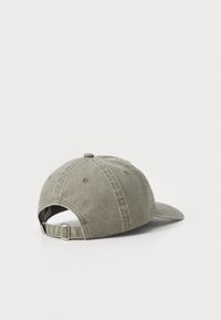 Khaki baseball cap made of cotton, featuring a curved brim, six-panel design, stitched details, and an adjustable metal strap at the back.