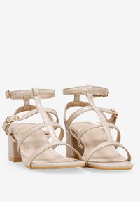 Sandalias de tacón bloque en color beige con tiras ajustables en el tobillo, material sintético liso, punta abierta y diseño de punta cuadrada.