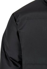 Jacheta puffer neagră cu un exterior neted și rezistent la apă. Prezintă un design matlasat și o cusătură bine definită la umăr. Textură moale.