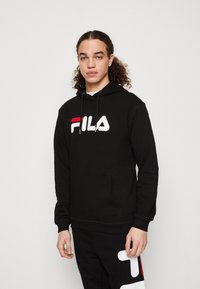 Felpa nera con logo "FILA" bianco e rosso, dotata di cappuccio con coulisse, tasca a marsupio frontale e polsini a costine, abbinata a joggers neri.