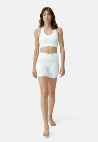 Top sportivo bianco e pantaloni corti abbinati con un sottile motivo a marmo. Design aderente, texture liscia e nessun hardware visibile.