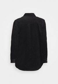 Chemise en velours côtelé noir avec un col boutonné, des manches longues et un ourlet arrondi avec un motif en relief.