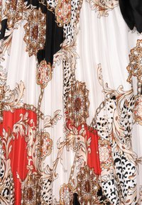 Faltenstoff mit einem floralen und Kettenmuster in Gold, Schwarz, Rot und Weiß, ergänzt durch kontrastierende Leopardenflecken. Glatte Textur.
