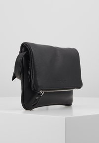 Černá kožená taška s texturovaným povrchem, která má překlopnou klopu a stříbrný zip. Kompaktní design s měkkými okraji.