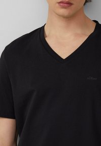 Zwarte katoenen V-hals T-shirt met korte mouwen en een subtiele s.Oliver-logo op de linkerkant van de borst. Glad textuur en klassieke pasvorm.