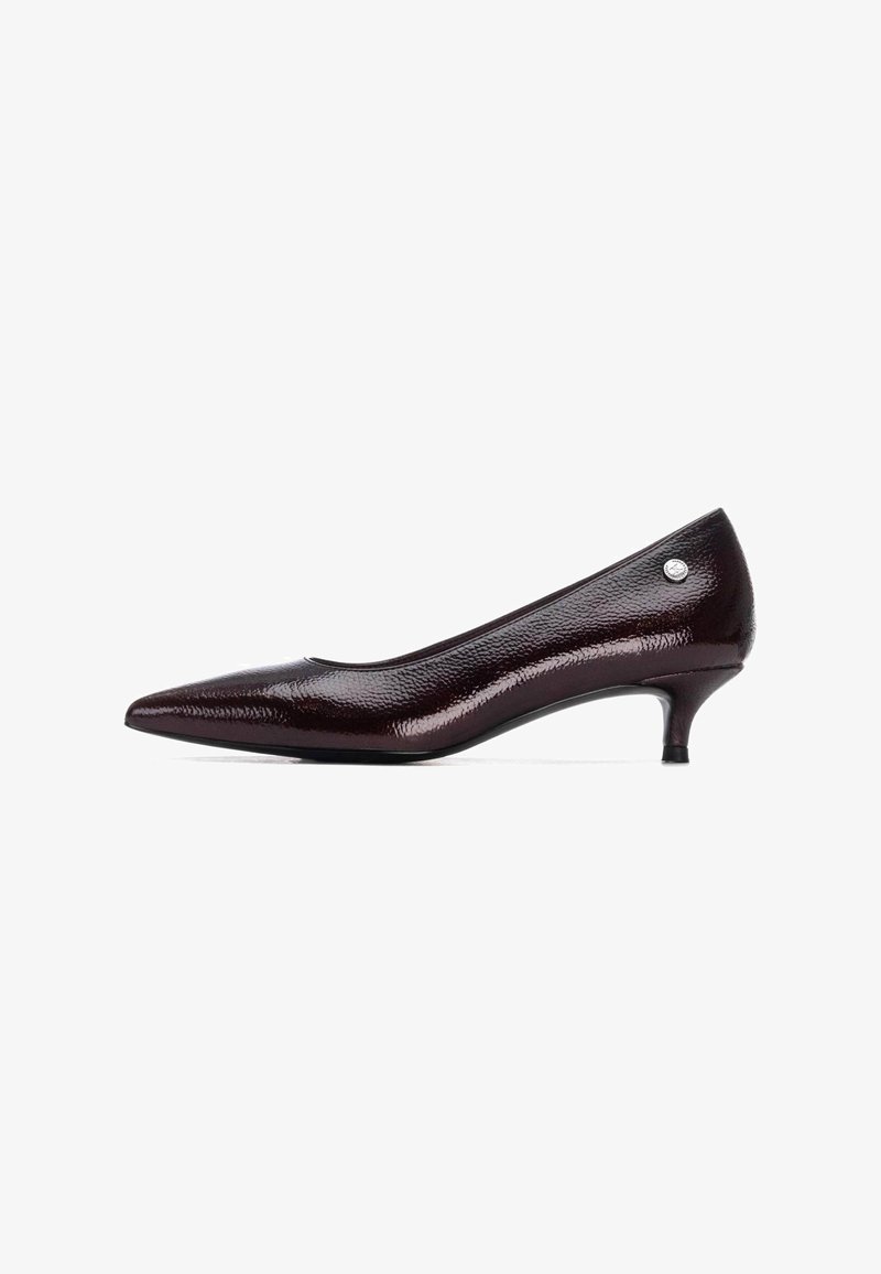 Zapato de charol burdeos oscuro con punta afilada, tacón bajo tipo kitten y sutil detalle en metal plateado en el lado del tacón.