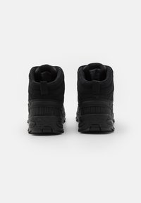 Sorte vandrestøvler med en struktureret overdel, polstret krave og gummisål. Har en træksnor og forstærkede sømme for holdbarhed.