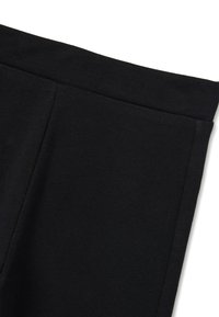 Pantalones elásticos negros con una textura suave, que cuentan con una cintura plana y sin cierres visibles, aptos para uso casual o activo.