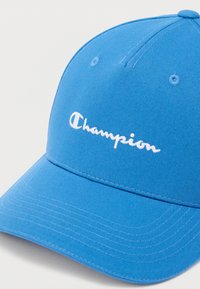 Μπλε καπέλο από βαμβάκι με κυρτή γείσο. Διαθέτει λευκό κεντητό λογότυπο "Champion". Υφή υφάσματος με ορατές ραφές.