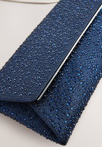 Navy blue clutch bag with a textured surface featuring numerous blue rhinestones, silver hardware, and a fold-over design.