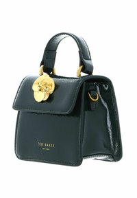 Sac à main en cuir verni vert avec une forme structurée, une poignée supérieure, des ferrures dorées et un accent floral décoratif sur le rabat.