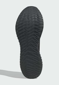 Sort skosål med tekstureret gummi, der har et zigzag-mønster for bedre greb. Lidt afrundede kanter og udtalt ydre kantdetalje.